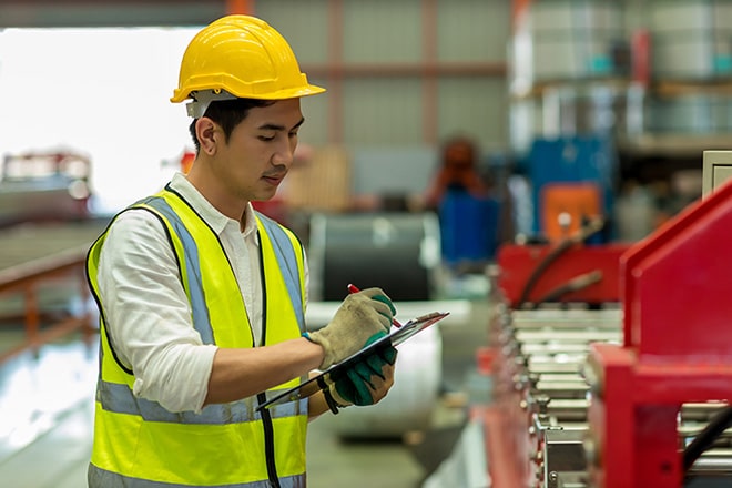An engineer in a safety helmet holding a clipboard, standing in an industrial facility. The image symbolizes the concept of Layers of Protection Analysis (LOPA), focusing on risk assessment and safety management.