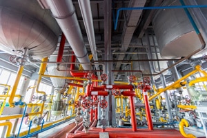 Industrial piping system with valves and tanks illustrating the role of Mechanical Asset Integrity in process safety and equipment reliability.