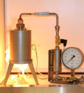 Combustible dust testing apparatus with pressure gauge and cylindrical test vessel in operation during NFPA and OSHA compliance testing